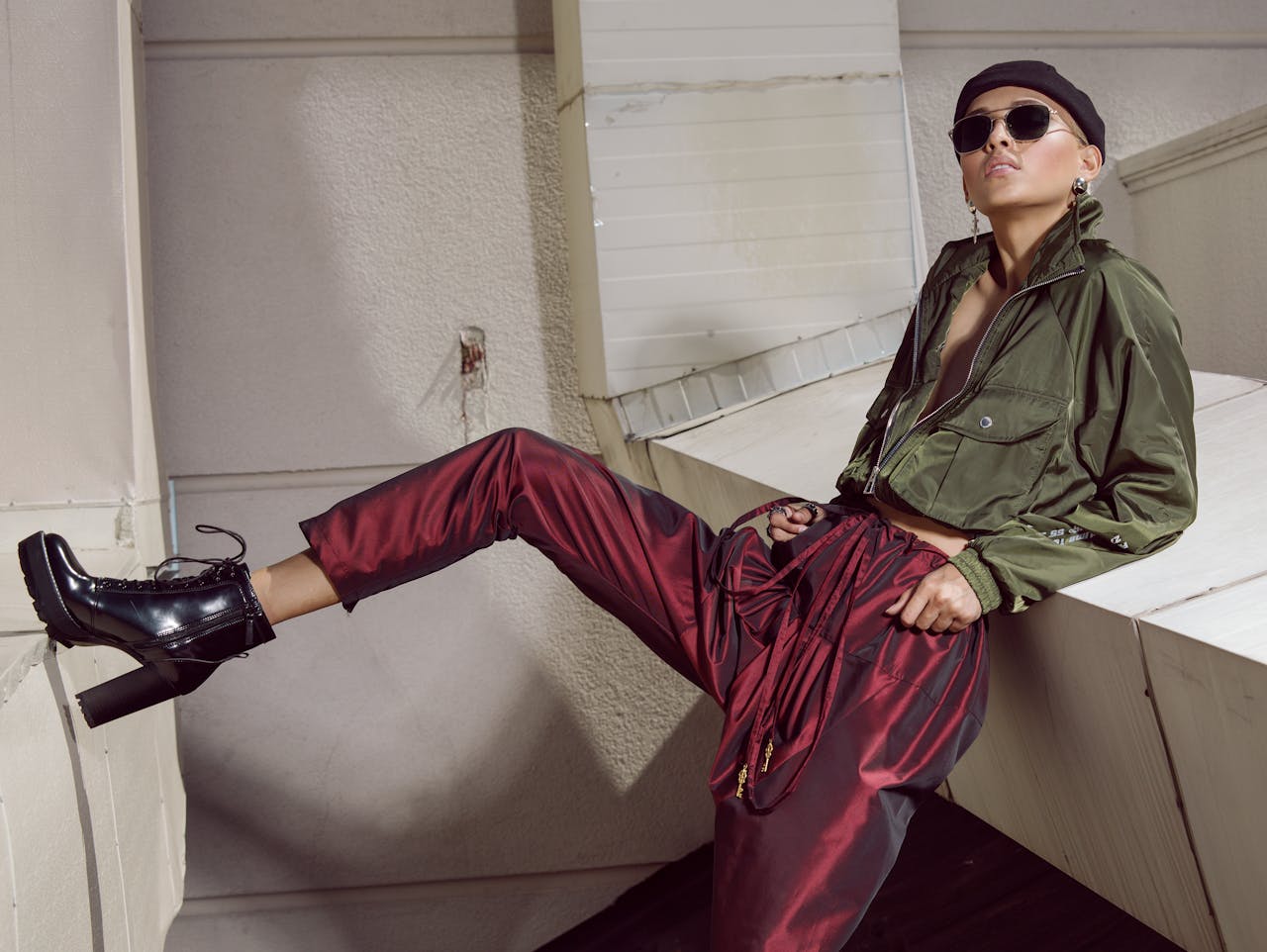 heros-img Young fashionable female wearing cool trendy clothes and boots leaning with back on white construction